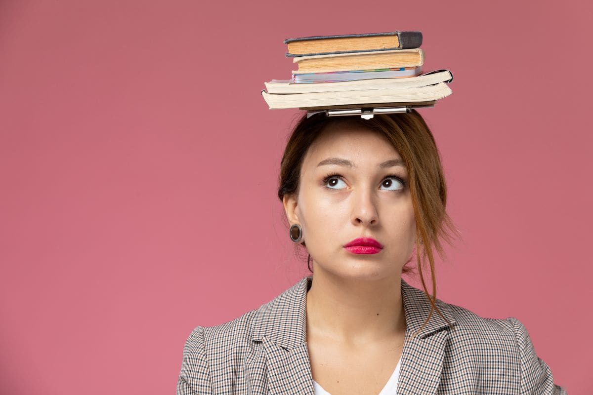 Front close view young female student in grey coat posing and holding book
