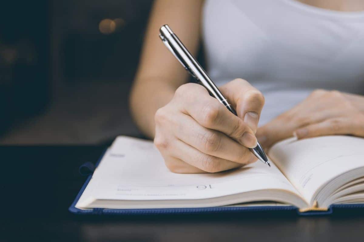 Foto di una persona che scrive su un quaderno