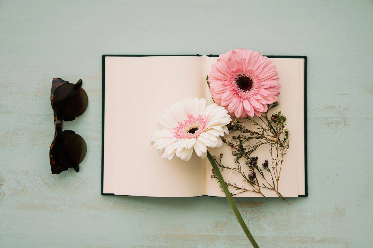 Sunglasses near notebook and flowers