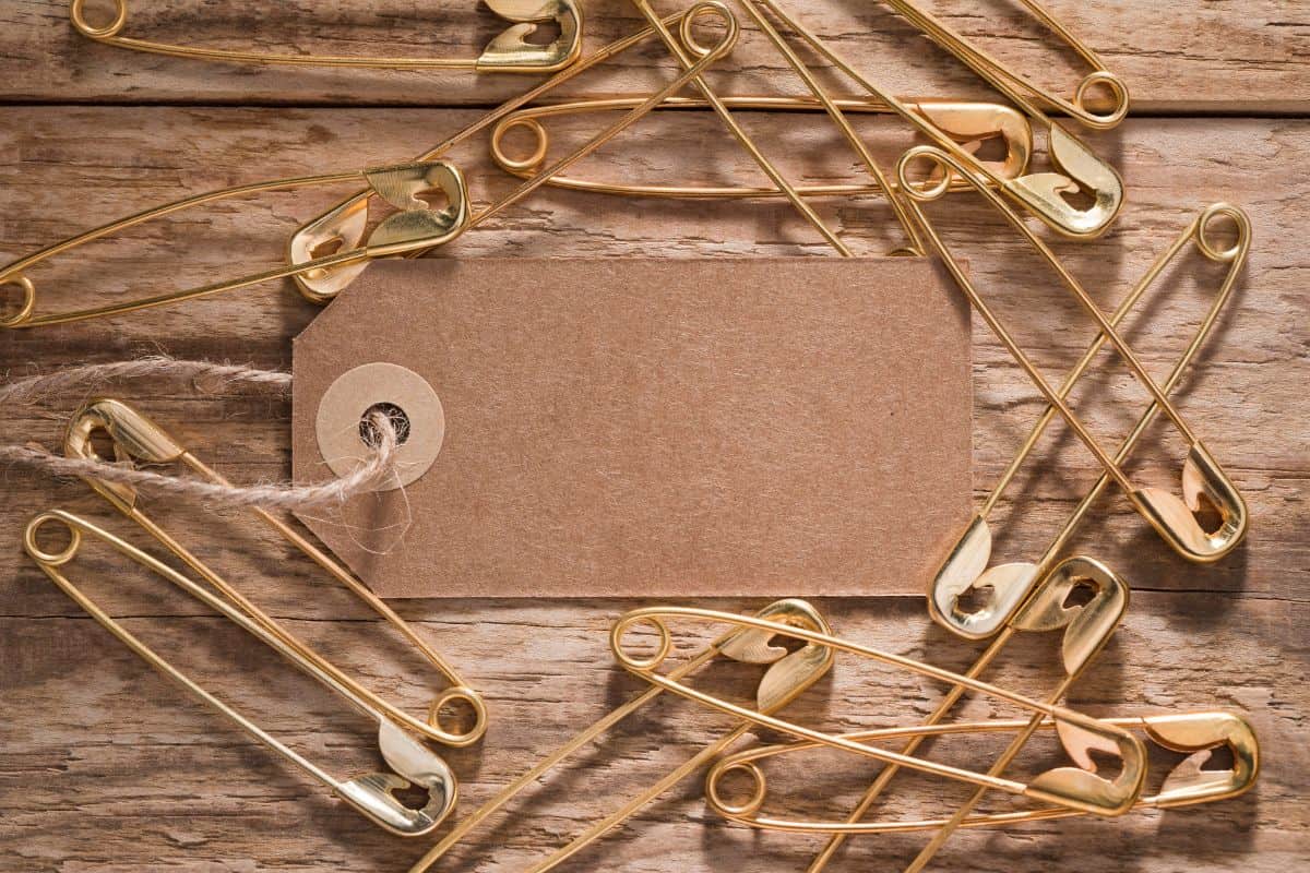 Top view of safety pins on wooden surface with tag
