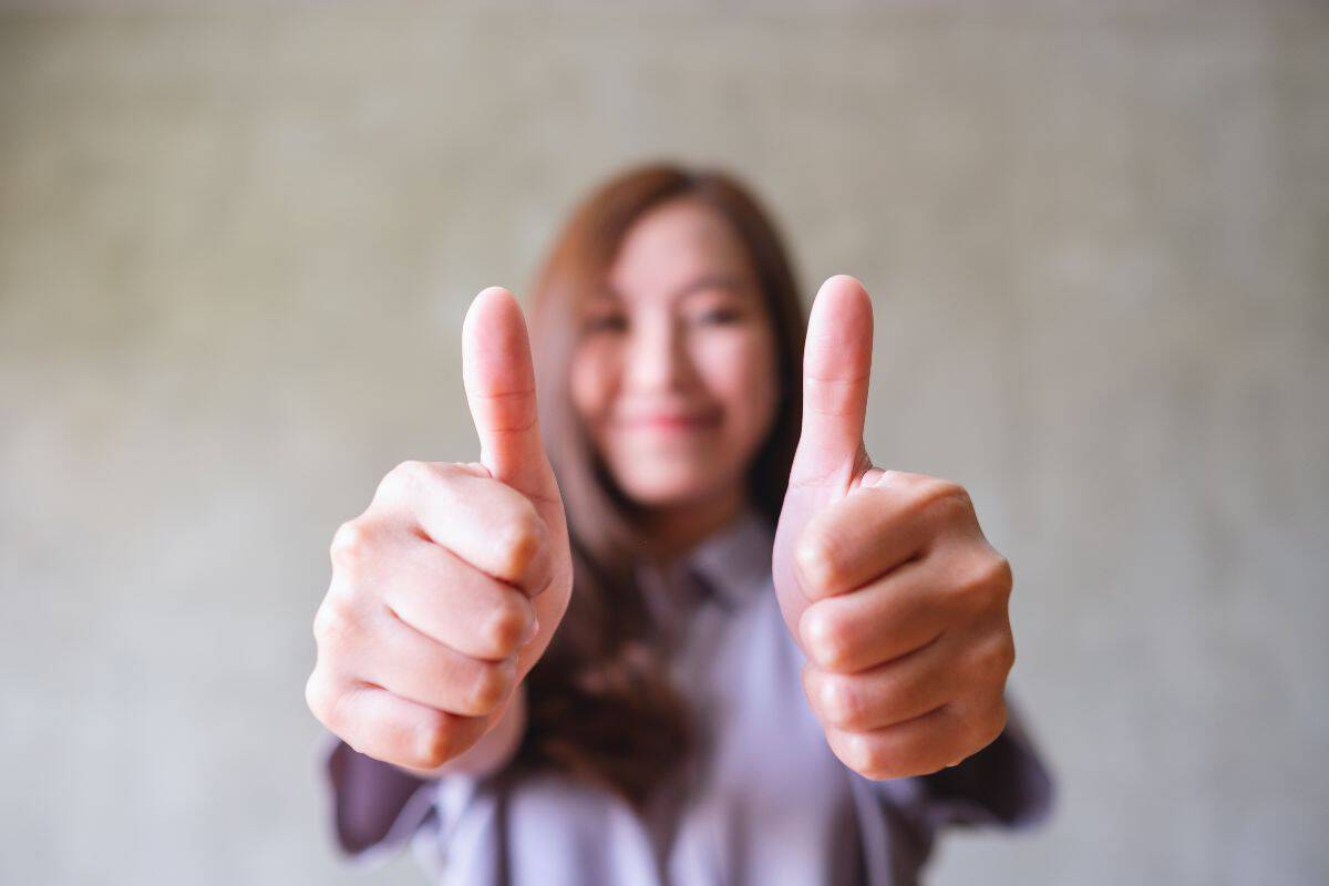 A young asian woman making and showing thumbs up hand sign