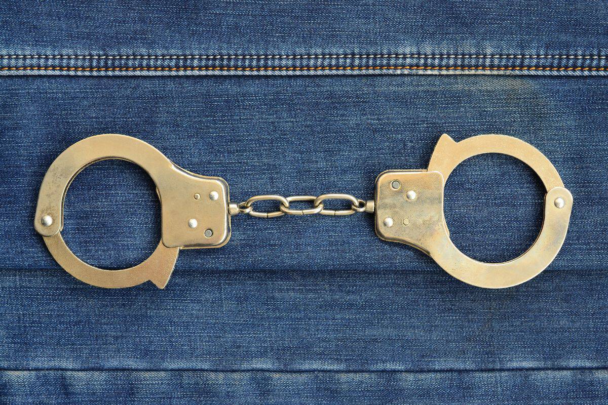 Police steel handcuffs lying on dark blue jeans background