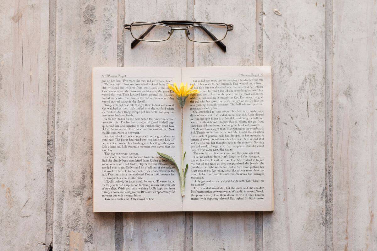 Open book with flower inside and glasses