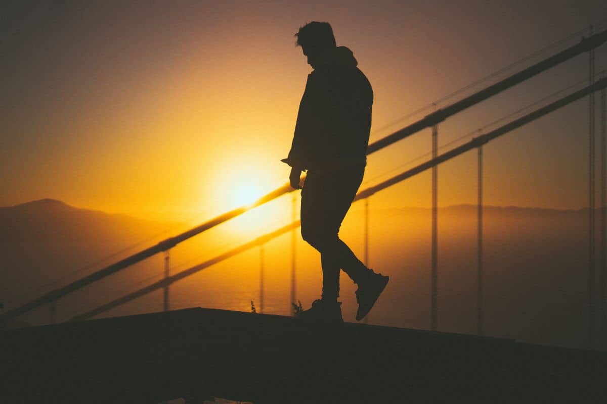 Silhouette of a young male walking on the staircase behind stair rails
