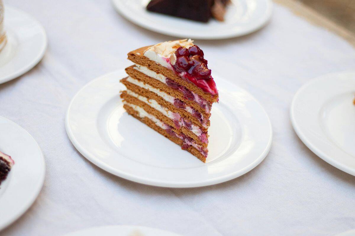 Delicious layered cake with cherry topping served on a white plate for dessert and celebration.