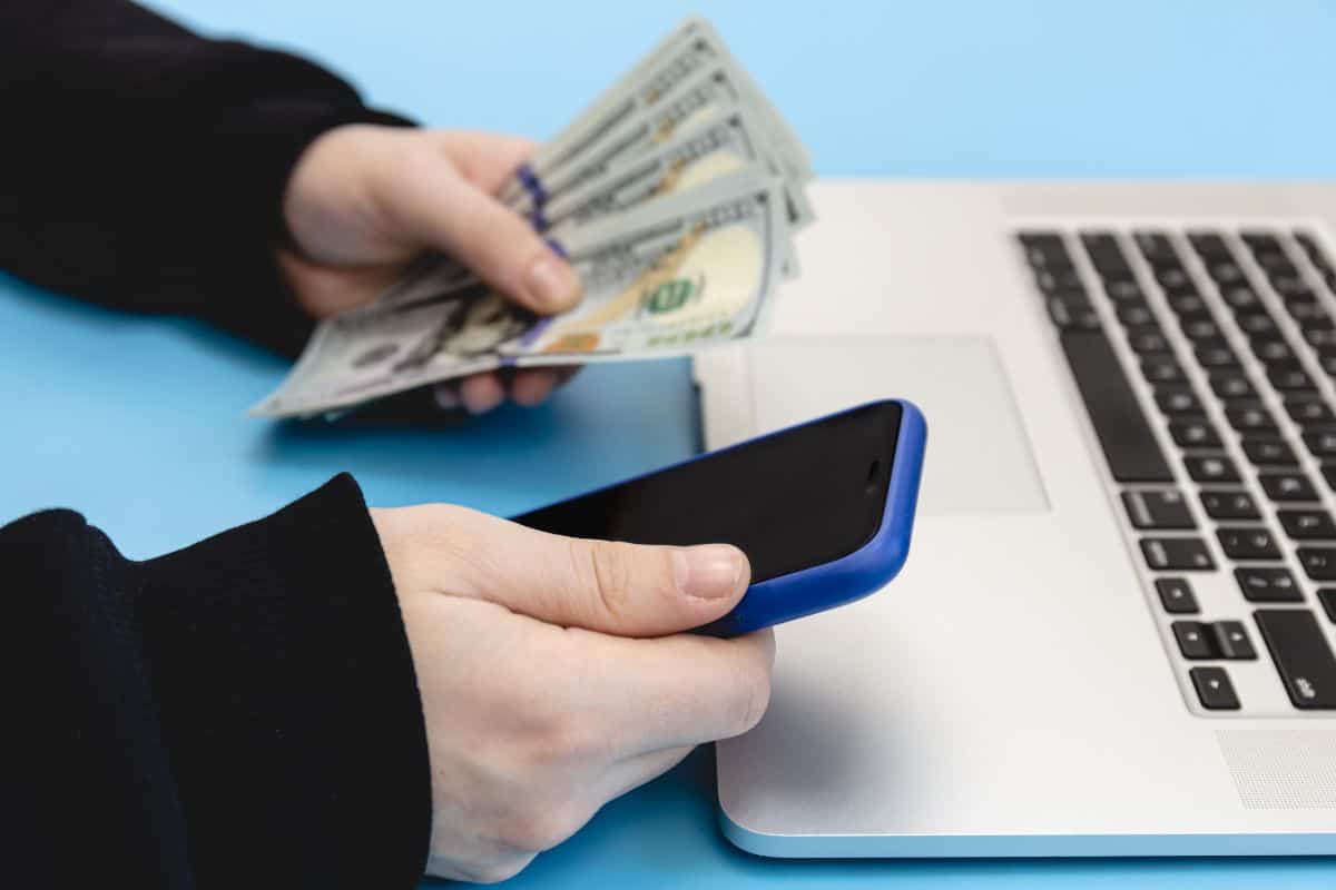 Laptop smartphone and money in male hands close up