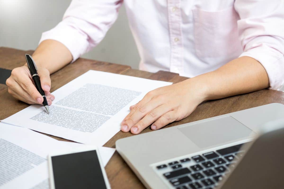 Midsection of man writing on document at table in office
