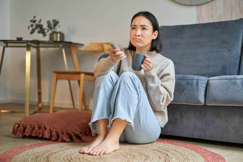 Como usar Skeptical ou Sceptical na redação 4 Retrato de uma garota assistindo à televisão em casa, sentada no chão
