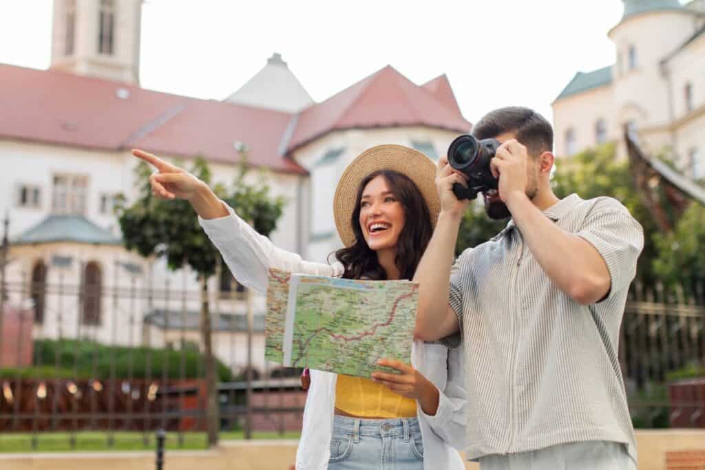 Casal de turistas entusiasmados passeando pela cidade usando um mapa de papel