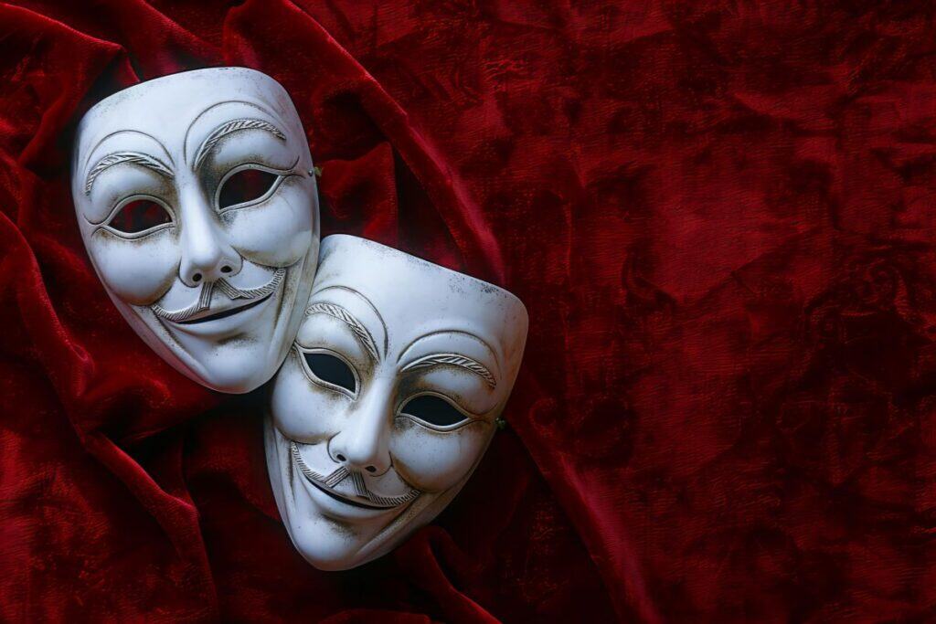 Por que a ortografia de Theatre vs. Theater é diferente 5 Um pano vermelho com máscaras brancas que dizem máscaras
