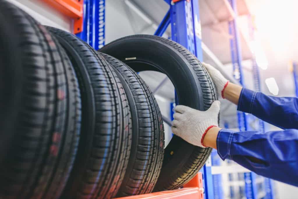 Pneu ou pneu: Qual é a diferença? 2 O mecânico de automóveis está trocando pneus novos no estoque