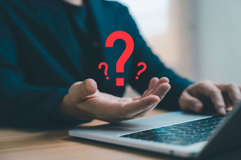
Businessman working on laptop with floating question mark symbol