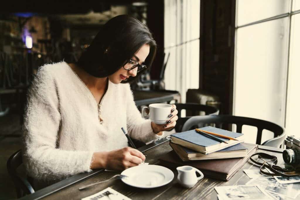 Por que a modelagem e a modelagem causam confusão 7 Garota de cabelos longos toma café em uma mesa de cafeteria