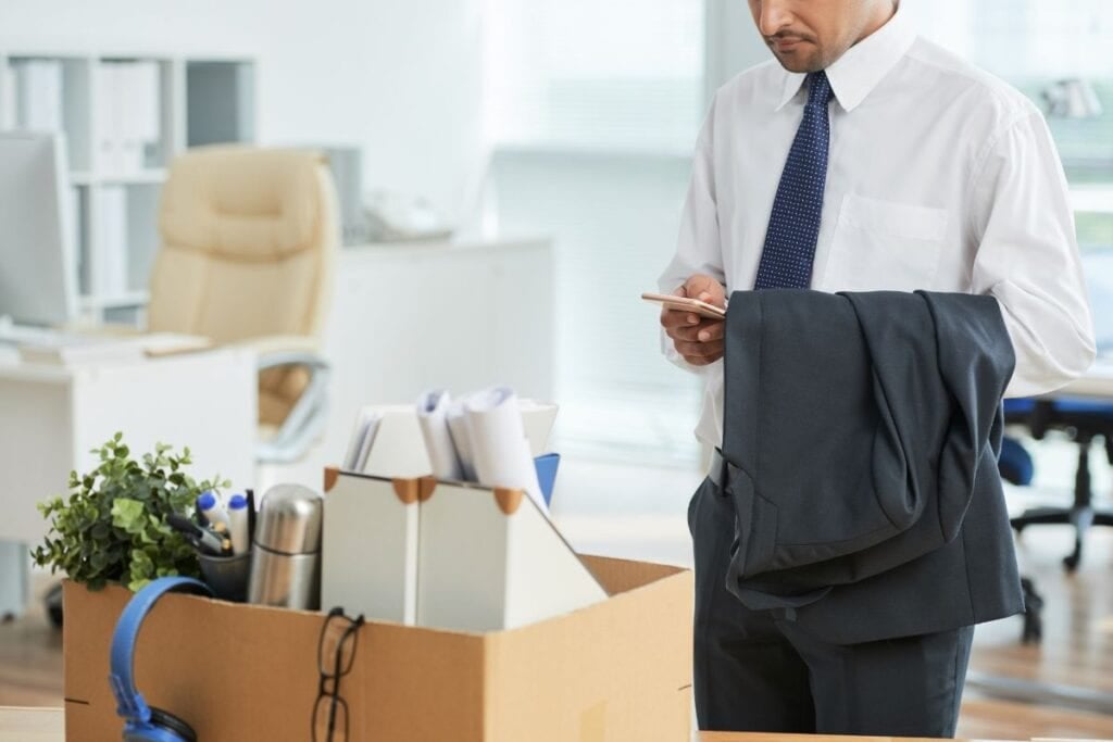 Unrecognizable man standing in office and using smartphone